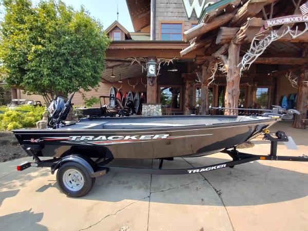 Tracker Super Guide V-16 T 2025 Tracker Super Guide V-16 T boat on trailer, parked outside rustic building.