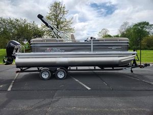 Sun Tracker Party Barge 22 RF DLX 2025 Sun Tracker Party Barge 22 RF DLX pontoon boat on trailer in parking lot.