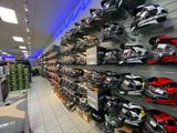 Store interior with rows of colorful motorcycle helmets on display shelves.