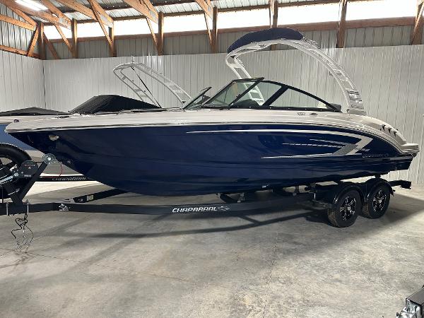 Chaparral 23 SSi 2025 Chaparral 23 SSi boat in storage, featuring sleek blue and white design.