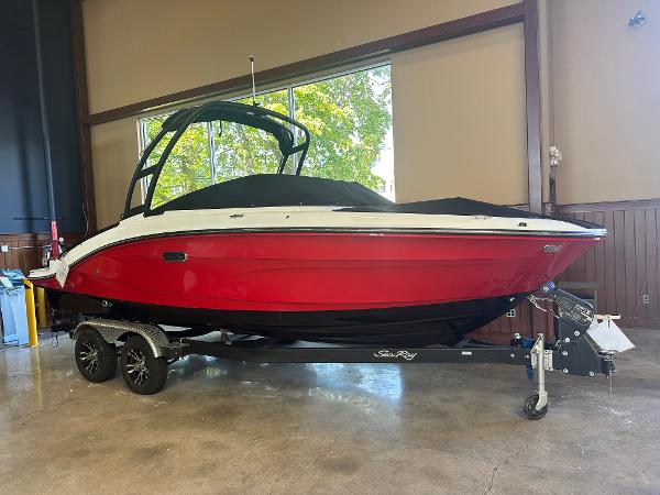 Sea Ray SPX 210 2024 Sea Ray SPX 210 boat with red hull on trailer indoors.