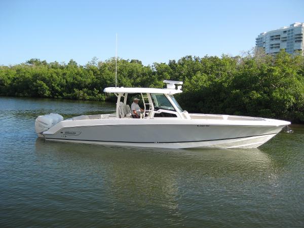 Boston Whaler 380 Outrage 2018 Boston Whaler 380 Outrage boat on calm water, surrounded by lush greenery.