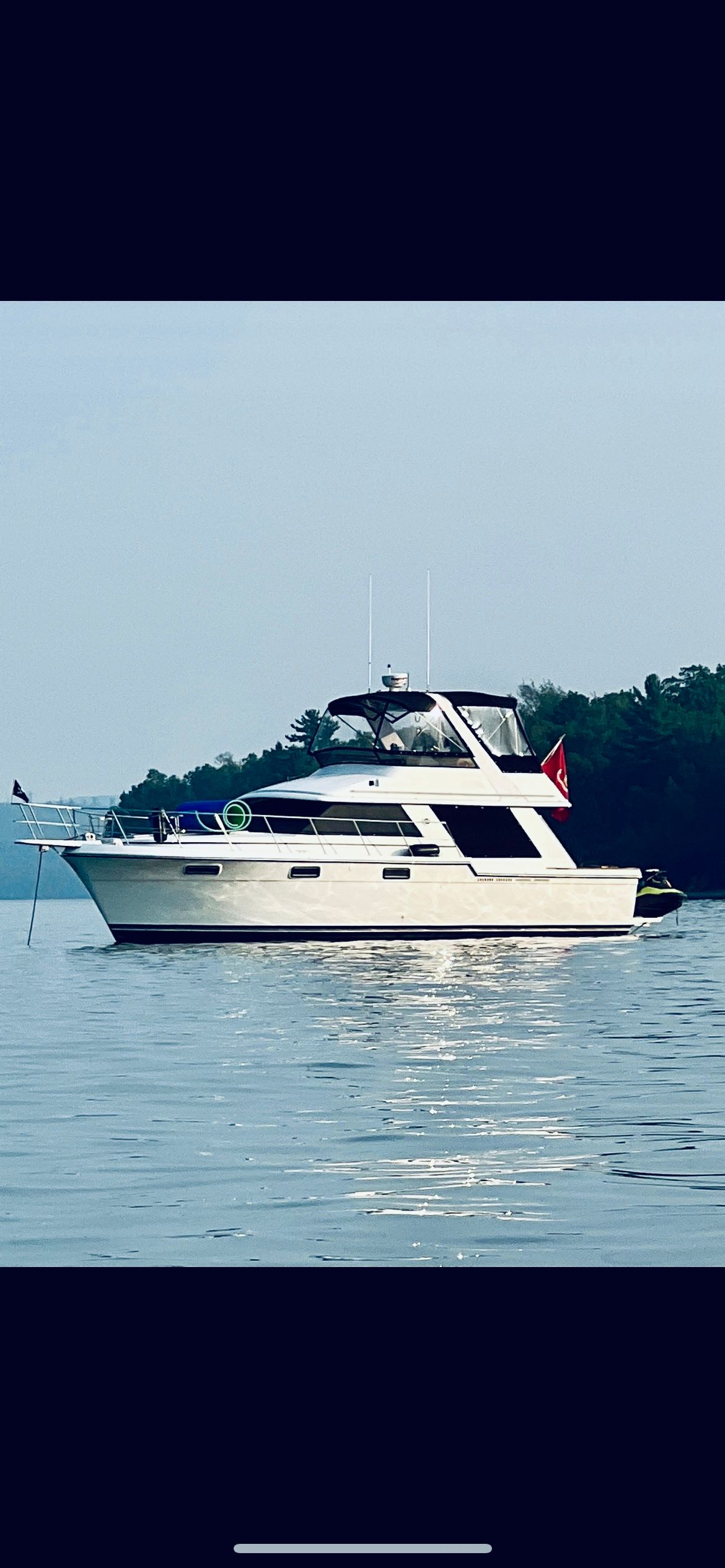 Carver 42 Cockpit Motor Yacht 1987 Carver 42 Cockpit Motor Yacht on calm water, surrounded by trees.