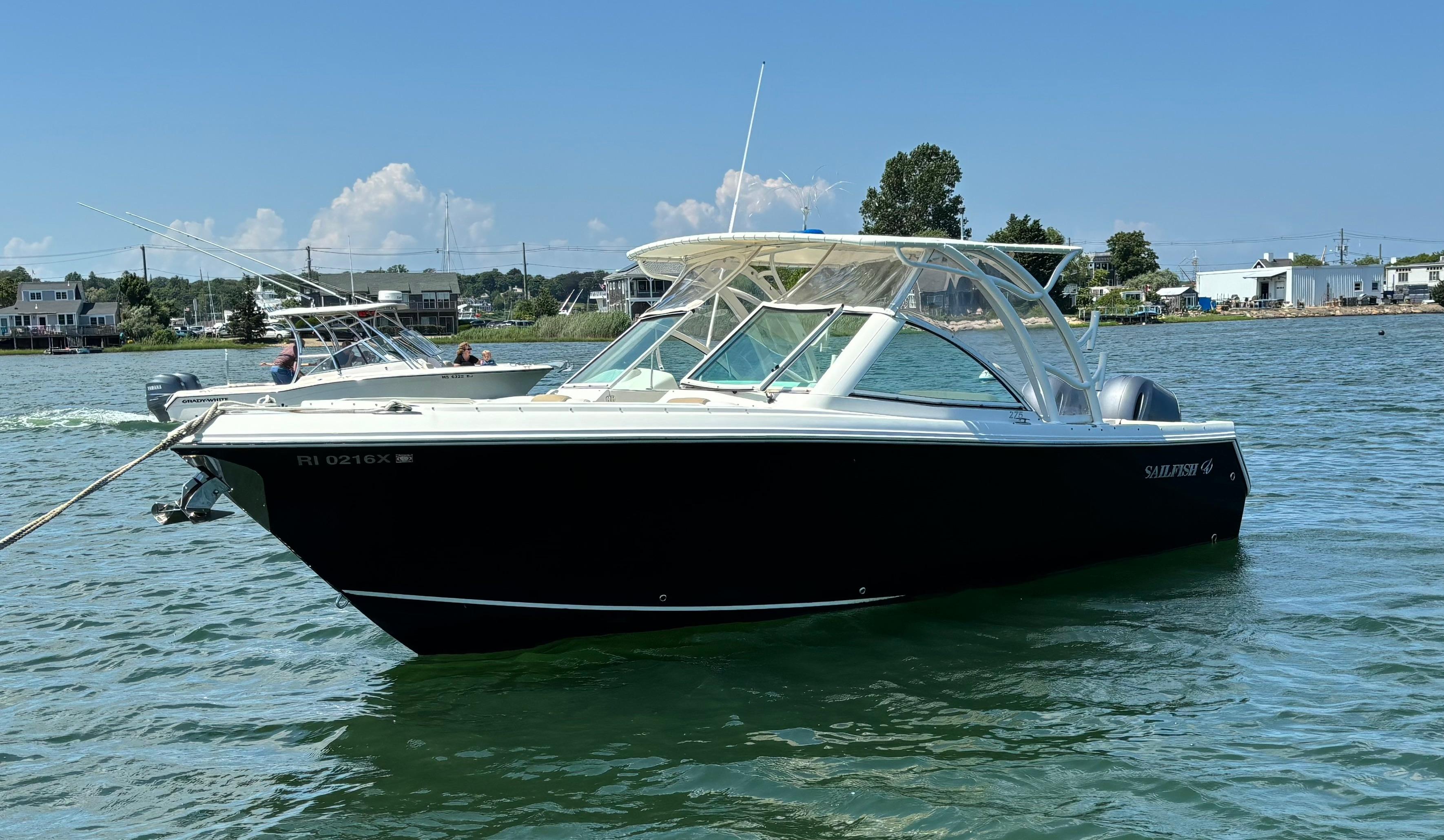 Sailfish 275 DC 2015 Sailfish 275 DC boat on calm water, clear sky, coastal background.