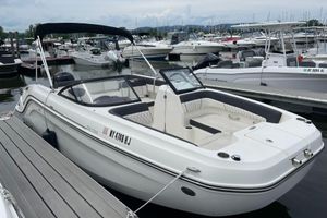 Bayliner DX 2200 2023 Bayliner DX 2200 boat docked at a marina, featuring sleek design and spacious seating.