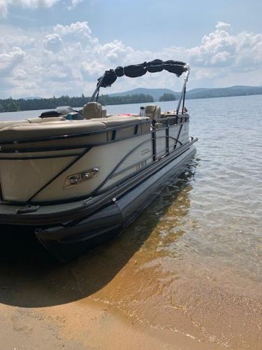 Regency 230 DL3 2020 Regency 230 DL3 pontoon boat on a sandy lakeshore under a cloudy sky.