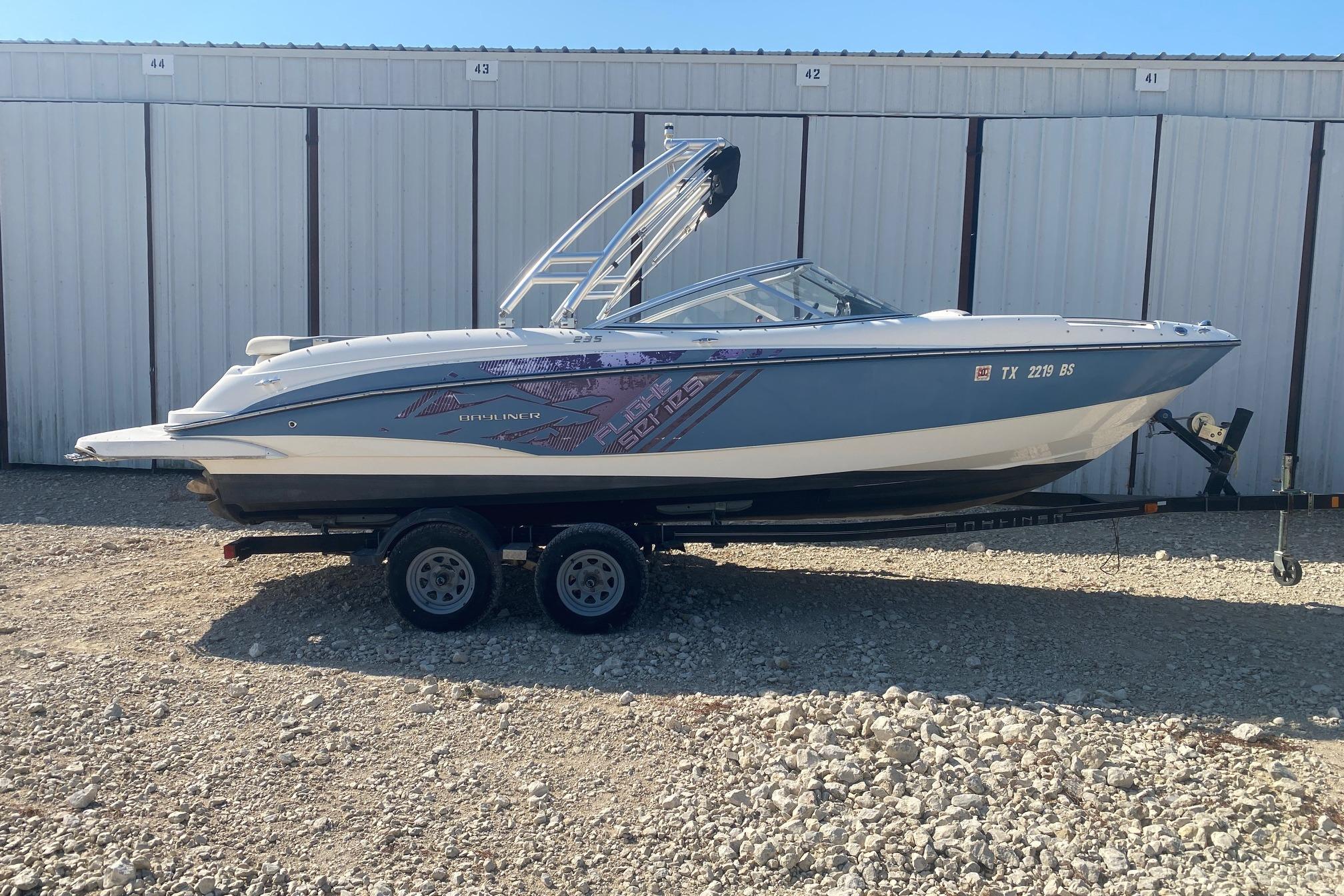 Bayliner 235 Bowrider 2012 Bayliner 235 Bowrider boat on trailer, parked in front of storage units.