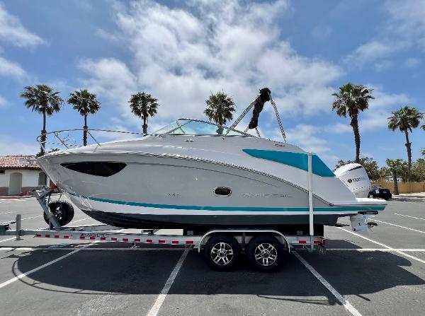 Regal 26 XO 2019 Regal 26 XO boat on trailer in sunny parking lot with palm trees.