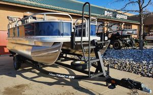 Sun Tracker Bass Buggy 16 XL Select 2025 Sun Tracker Bass Buggy 16 XL Select pontoon boat on trailer outside service center.