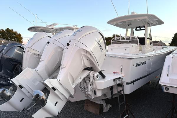 Regulator 34 2024 Regulator 34 boat with twin Yamaha outboard engines, docked on gravel.