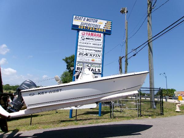 Key West 1720 Cc Key West 1720 boat near dealership sign, showcasing various marine brands.