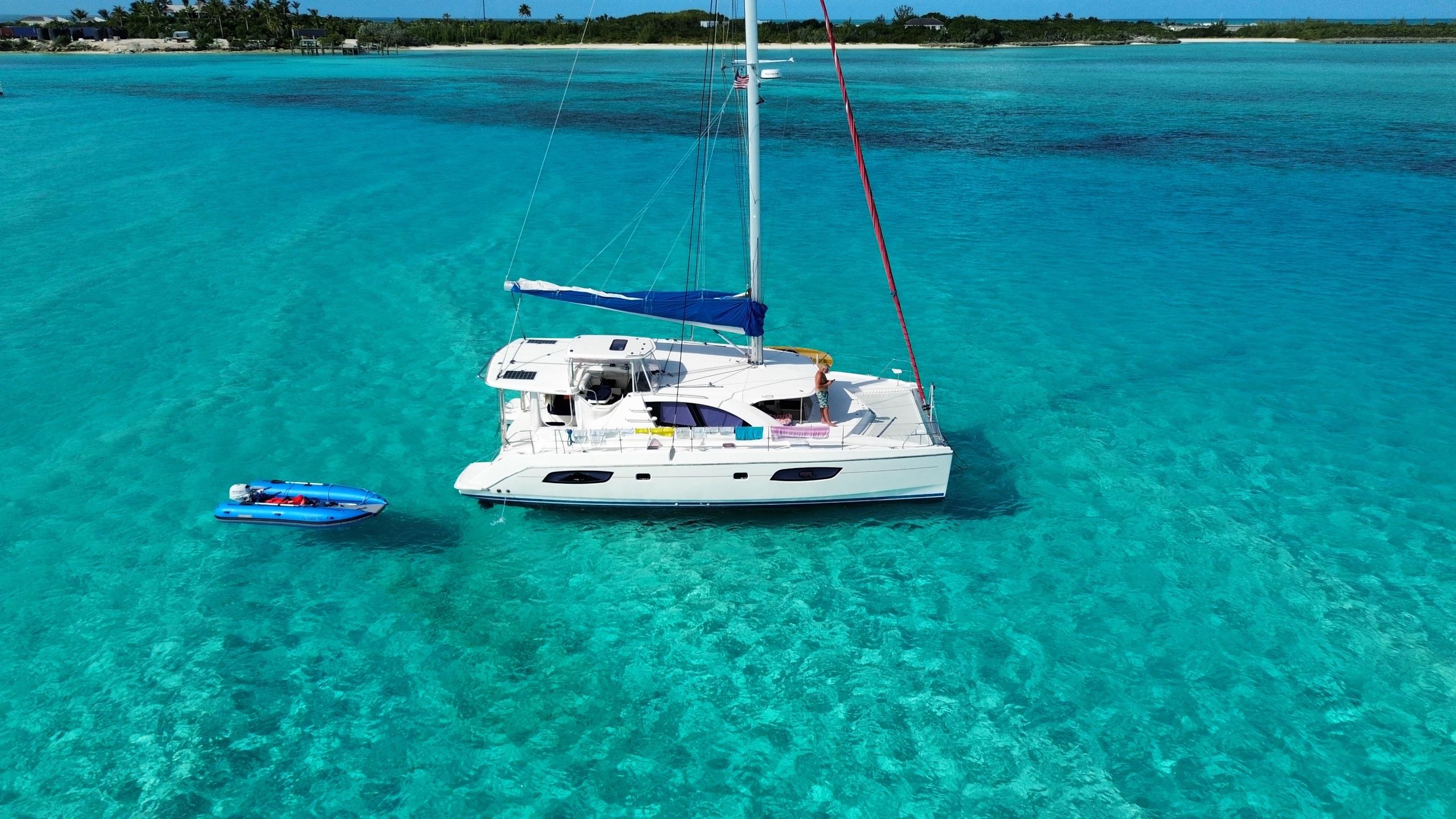 Leopard 44 Catamaran Leopard 44 sailing in clear turquoise waters, 2013 model, with a small blue dinghy nearby.