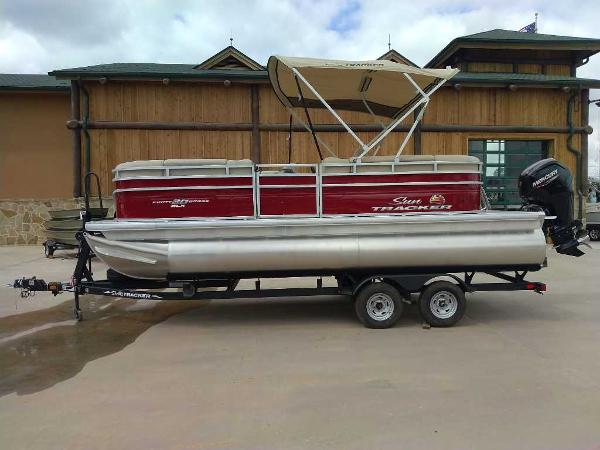 Sun Tracker Party Barge 20 DLX 2025 Sun Tracker Party Barge 20 DLX pontoon boat on trailer, parked outdoors.