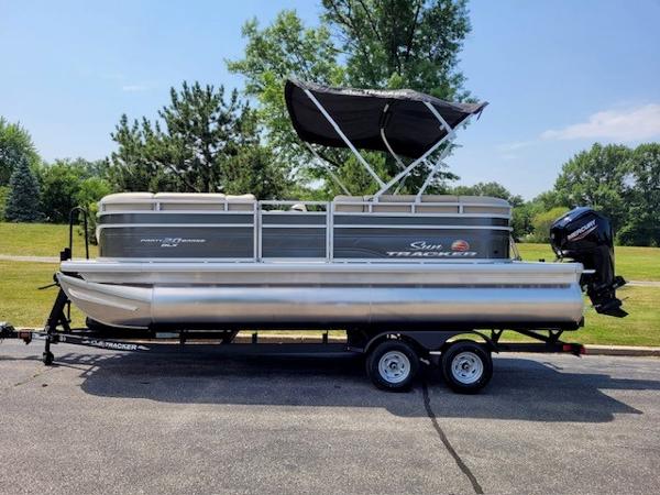 Sun Tracker Party Barge 20 DLX 2024 Sun Tracker Party Barge 20 DLX pontoon boat on trailer, parked outdoors.