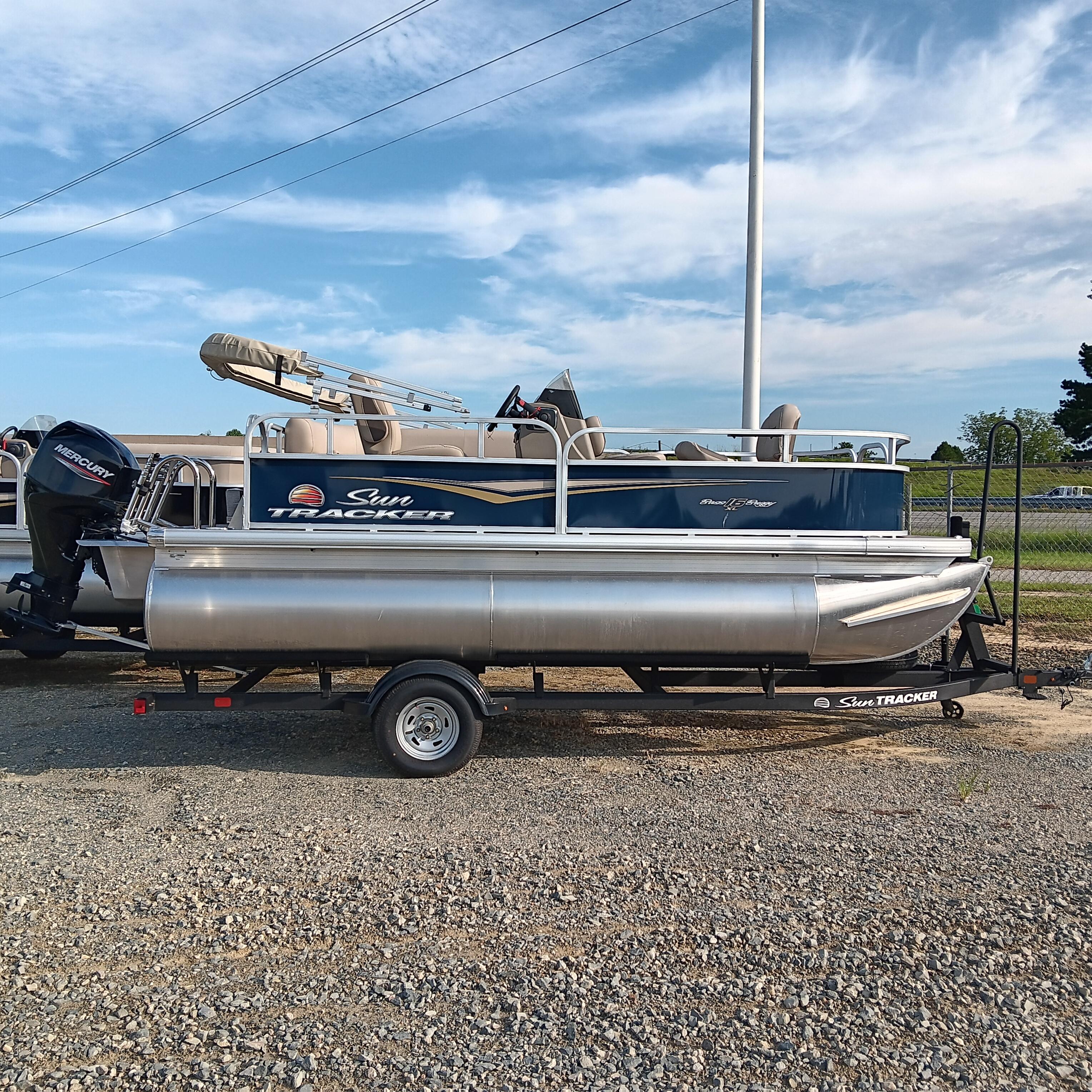 Sun Tracker Bass Buggy 16 XL Select 2025 Sun Tracker Bass Buggy 16 XL Select pontoon boat on trailer, parked outdoors.
