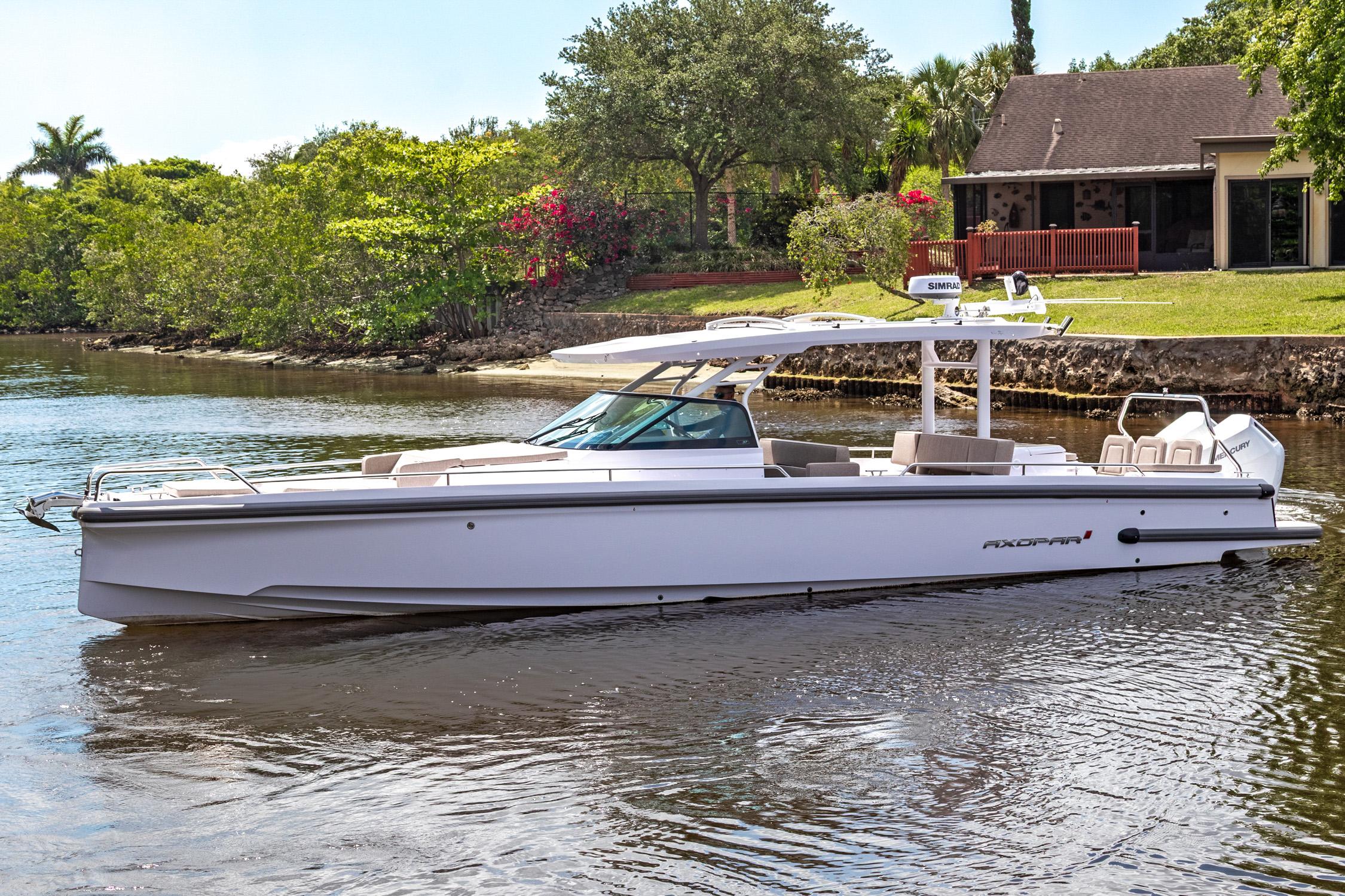 Axopar 37 Sun Top 2025 Axopar 37 Sun Top boat on a serene waterway near a lush, green landscape.
