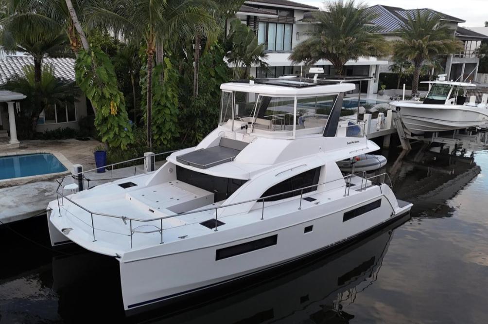 Leopard 43PC 2018 Leopard 43PC catamaran docked by waterfront homes, surrounded by lush palm trees.