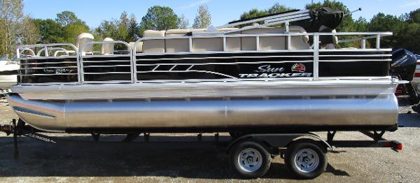 Sun Tracker Fishin' Barge 20 DLX 2025 Sun Tracker Fishin' Barge 20 DLX pontoon boat on trailer, parked outdoors.