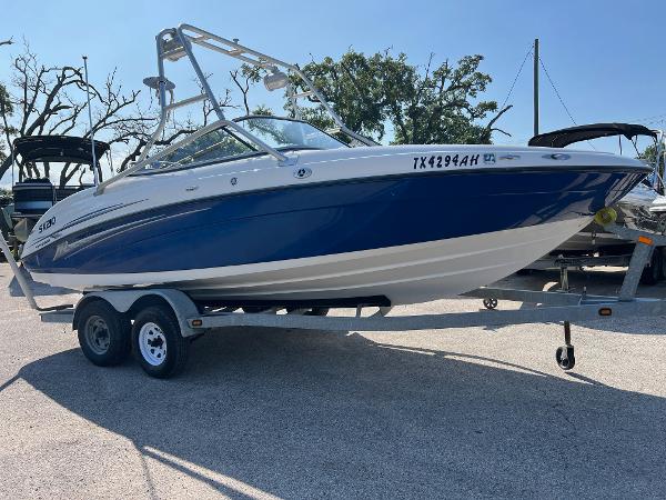 Yamaha Boats SX210 2006 Yamaha SX210 boat on trailer, blue and white design, parked outdoors.