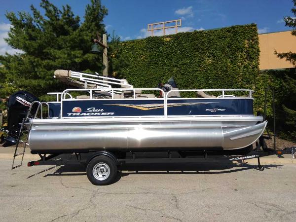 Sun Tracker Bass Buggy 18 DLX 2025 Sun Tracker Bass Buggy 18 DLX pontoon boat on trailer, parked outdoors.
