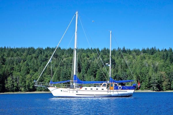 Custom Motor Sailer Ketch 50’ Pilothouse 1975 Custom Motor Sailer Ketch 50’ Pilothouse on serene blue water, forested background.