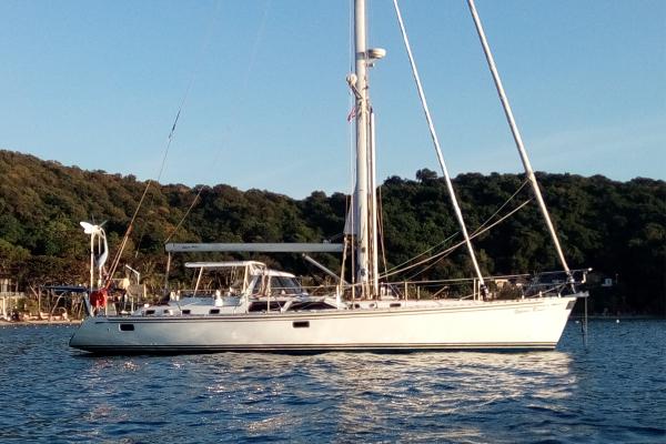 Hylas 54 2004 Hylas 54 sailboat on calm water with forested shoreline in the background.