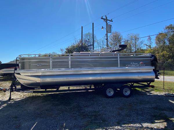 Sun Tracker Fishin' Barge 22 DLX 2025 Sun Tracker Fishin' Barge 22 DLX pontoon boat on trailer, parked outdoors.
