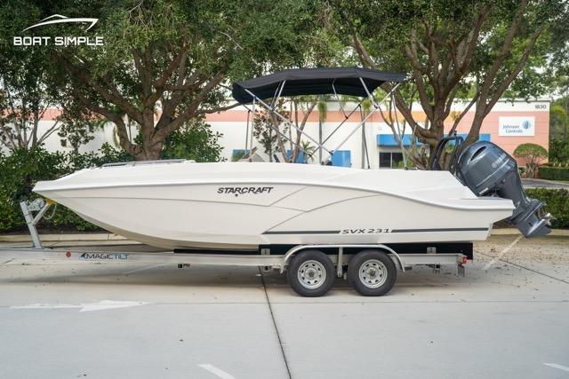 Starcraft SVX 231 OB DH 2023 Starcraft SVX 231 OB DH boat on trailer, parked outdoors with trees in background.