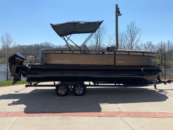 Regency 230 DL3 2024 Regency 230 DL3 pontoon boat on trailer, parked outdoors under clear sky.
