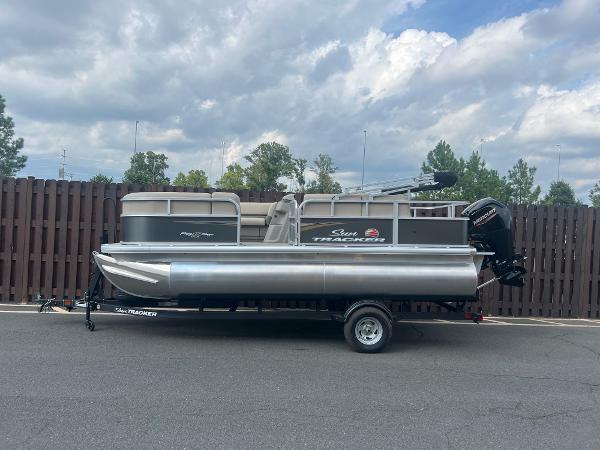 Sun Tracker Party Barge 18 DLX 2025 Sun Tracker Party Barge 18 DLX pontoon boat on trailer, parked outdoors.
