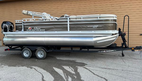 Sun Tracker SportFish 20 DLX 2025 Sun Tracker SportFish 20 DLX pontoon boat on trailer, parked outdoors.
