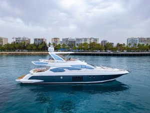 Azimut 64 2014 Azimut 64 yacht cruising near urban waterfront under cloudy skies.