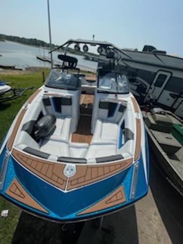 Nautique Super Air Nautique G23 2017 Nautique Super Air Nautique G23 boat with blue and white design, docked by a lake.