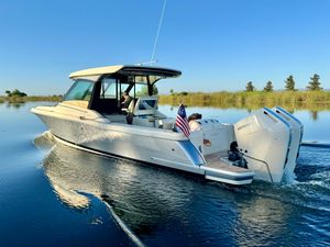 Chris-Craft Calypso 32 2024 Chris-Craft Calypso 32 cruising on a serene lake with clear blue skies.