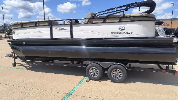 Regency 230 DL3 2024 Regency 230 DL3 pontoon boat on a trailer in a parking lot.
