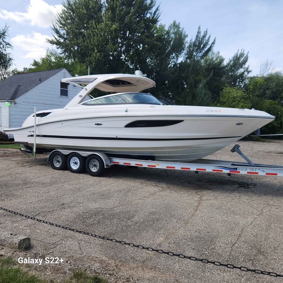 Sea Ray 350 SLX 2014 Sea Ray 350 SLX boat on trailer, parked outdoors near trees and house.