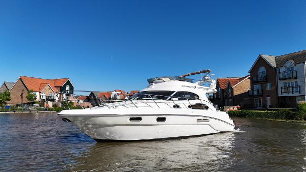 Sealine F37 2008 Sealine F37 yacht cruising near waterfront homes under clear blue sky.
