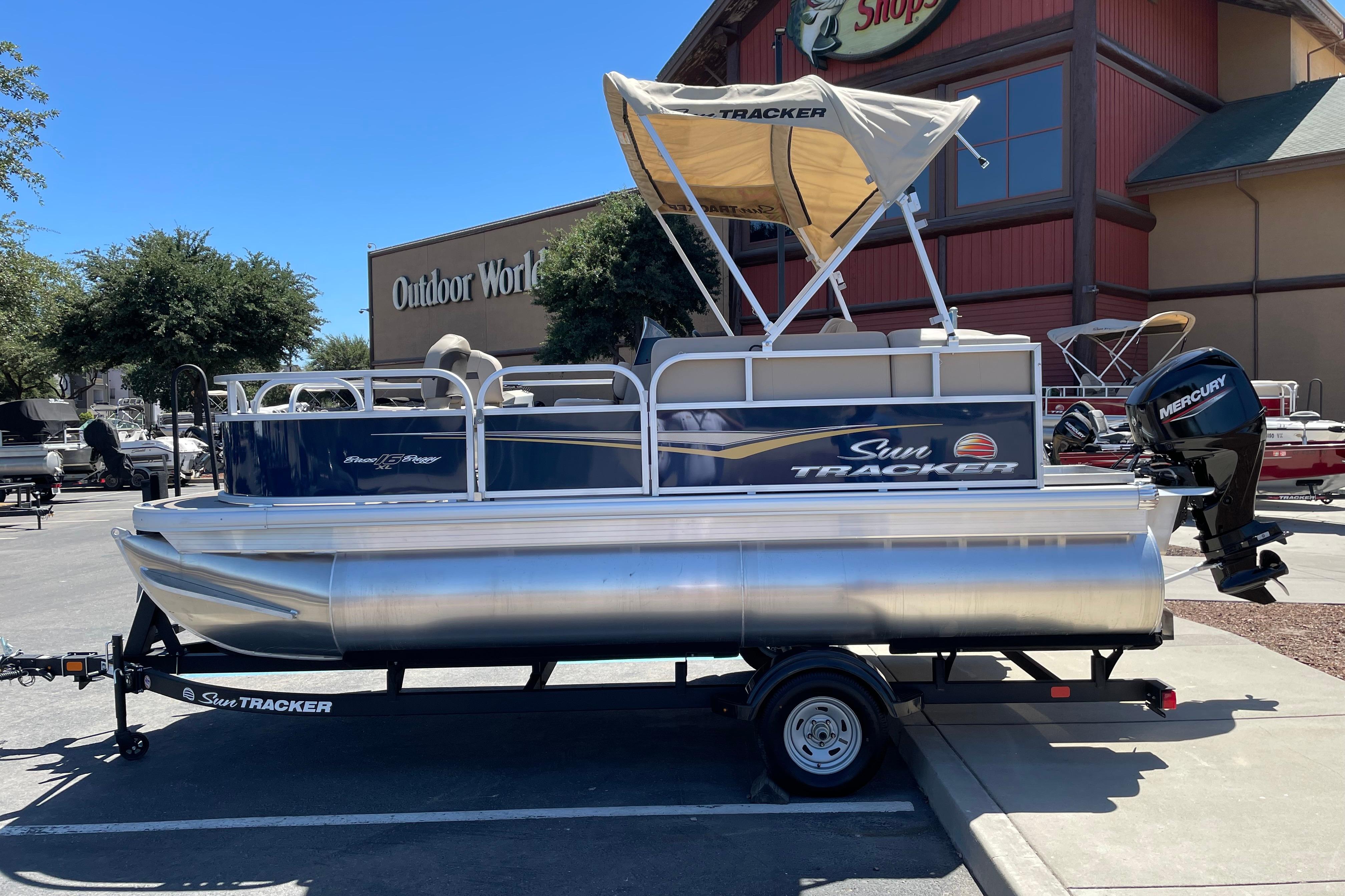 Sun Tracker Bass Buggy 16 XL Select 2025 Sun Tracker Bass Buggy 16 XL Select pontoon boat on trailer, outdoor store background.