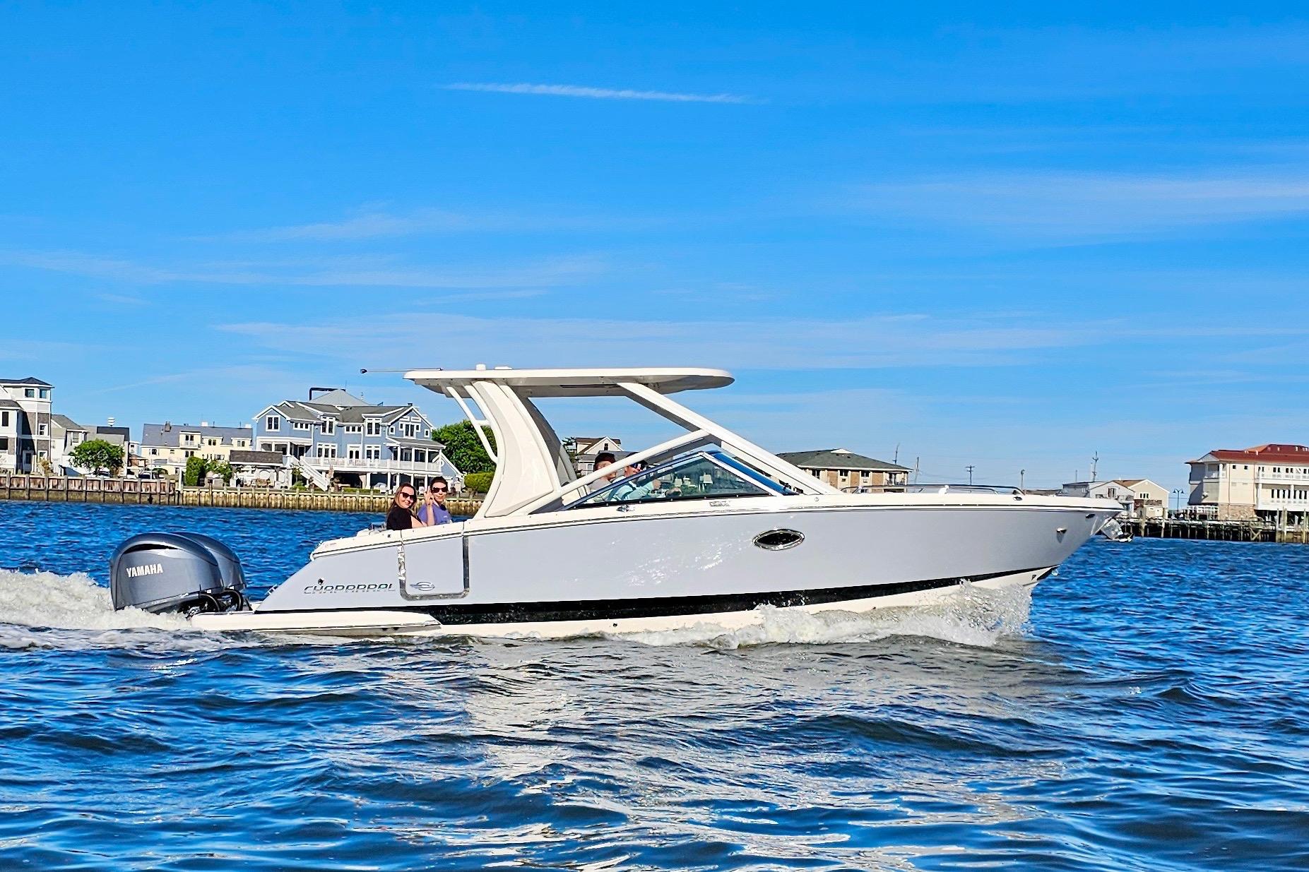 Chaparral 280 OSX 2023 Chaparral 280 OSX boat cruising on a sunny day near waterfront homes.