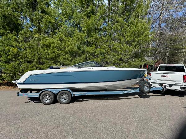 Cobalt CS23 2024 Cobalt CS23 boat on trailer, towed by GMC truck, parked near trees.