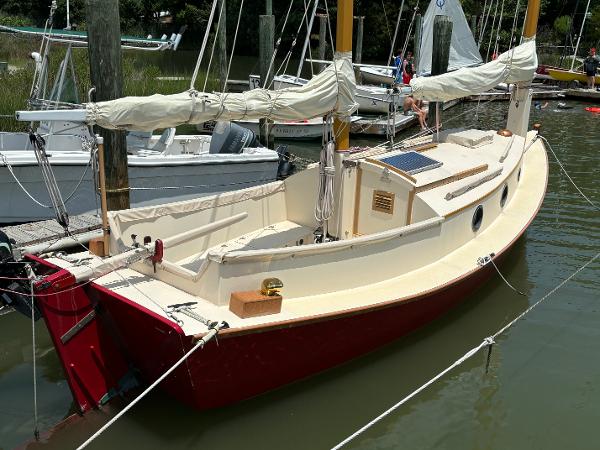 Custom Cat Ketch Custom 2011 Cat Ketch sailboat docked, featuring red hull and cream deck.