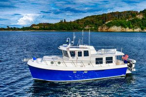 American Tug 41 2007 American Tug 41 cruising on a scenic lake with lush green shoreline.