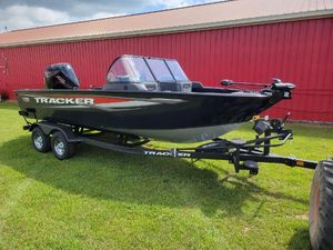 Tracker Targa V-19 WT 2025 Tracker Targa V-19 WT boat on trailer, parked on grass by red building.