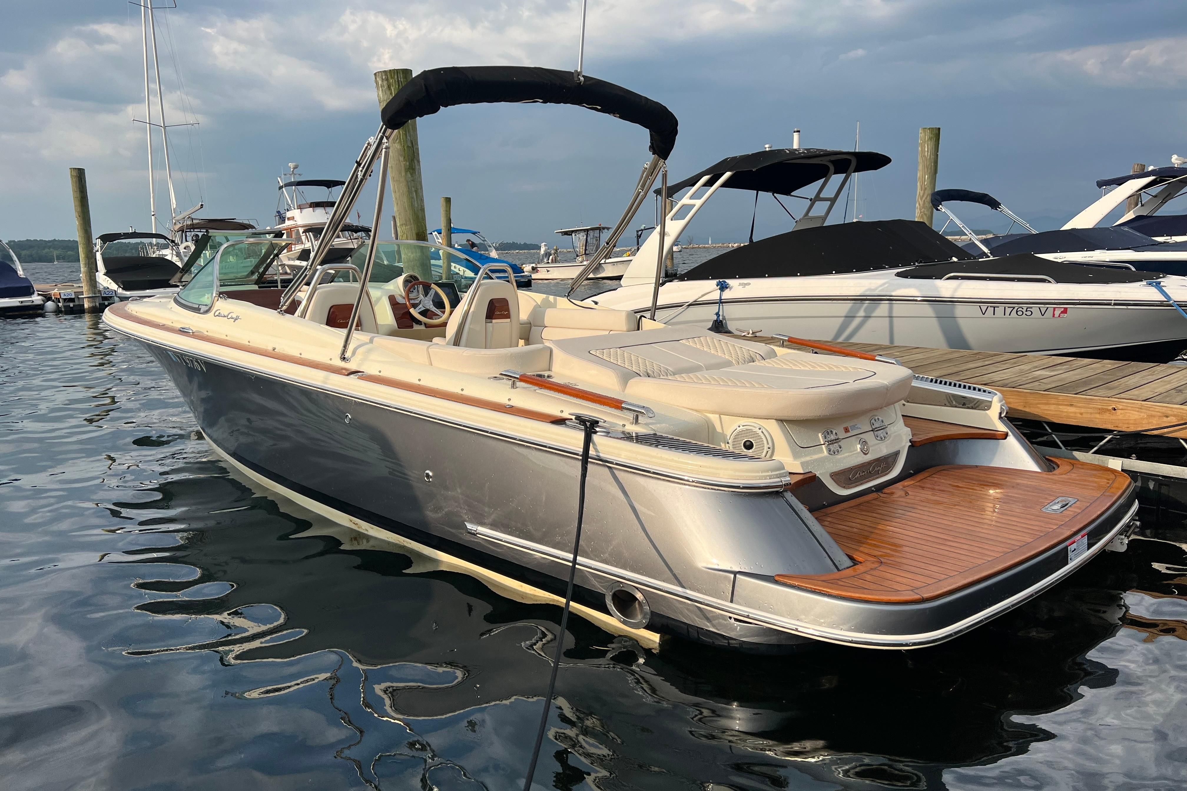 Chris-Craft Launch 25 GT 2021 Chris-Craft Launch 25 GT boat docked in marina, featuring sleek design and wooden deck.