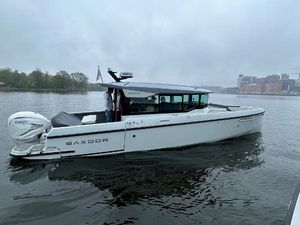 Saxdor 320 GTC 2022 Saxdor 320 GTC boat on a calm river with cityscape background.