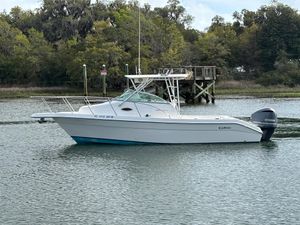 Cobia 230WA 1997 Cobia 230WA boat on calm water near a wooden dock, surrounded by trees.