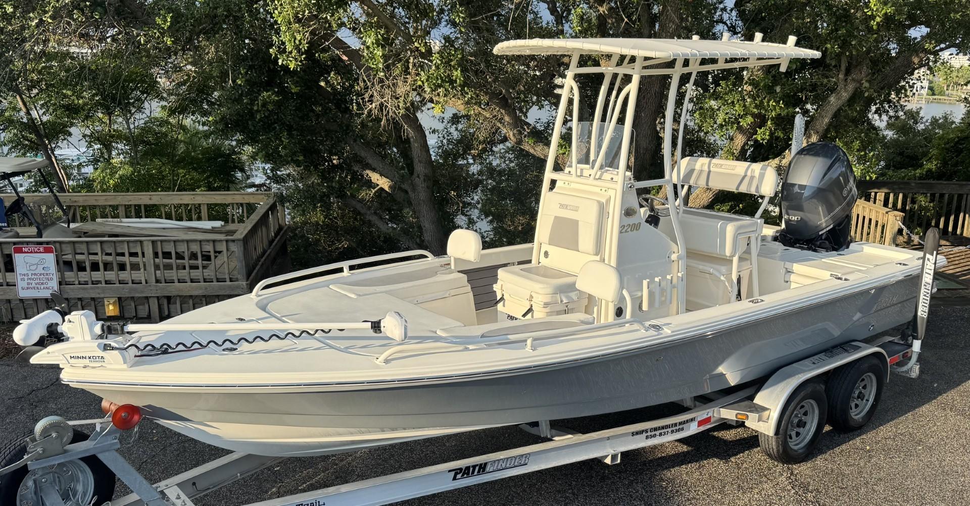 Pathfinder 2200 TRS 2023 Pathfinder 2200 TRS boat on trailer, parked near trees.