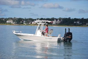 Key West 210 Bay Reef 2021 Key West 210 Bay Reef boat on calm water, with scenic shoreline background.