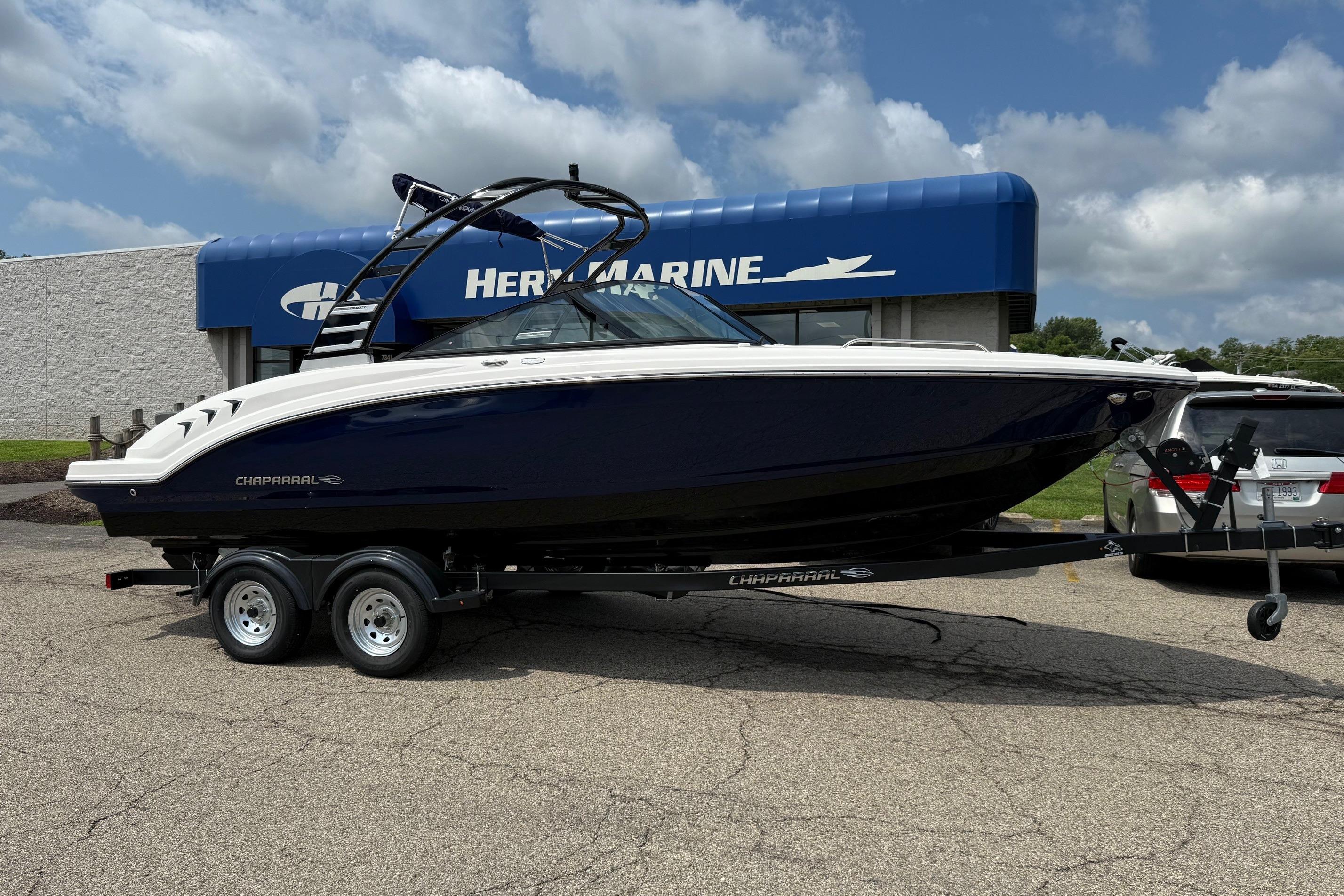 Chaparral 23 SSi 2025 Chaparral 23 SSi boat on trailer outside marine dealership.