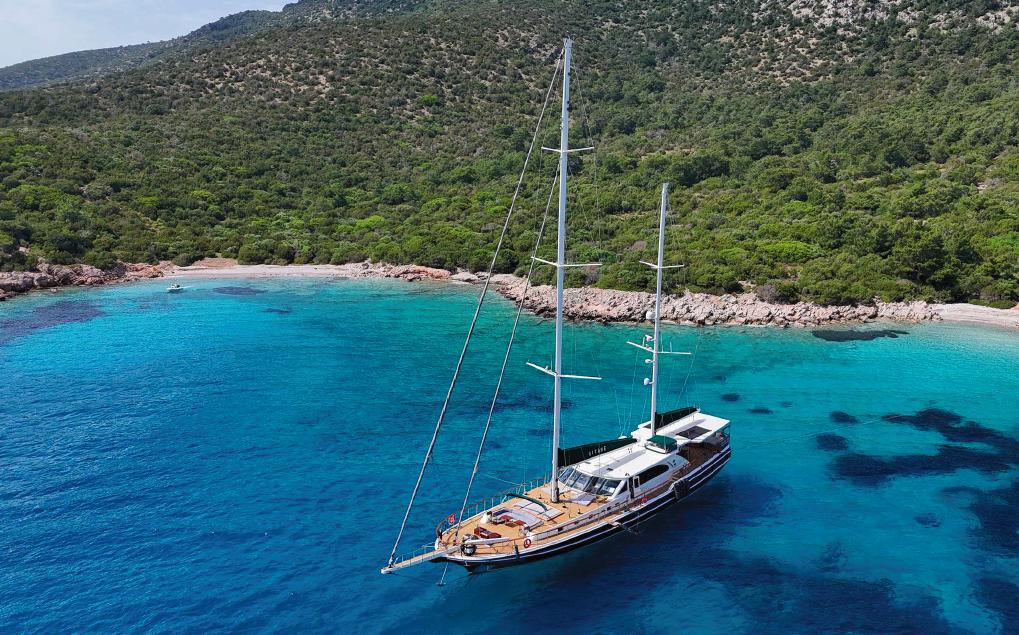 Evadne 37mt Sailing yacht Evadne 37mt, 2008, anchored in a serene turquoise bay with lush green hills.